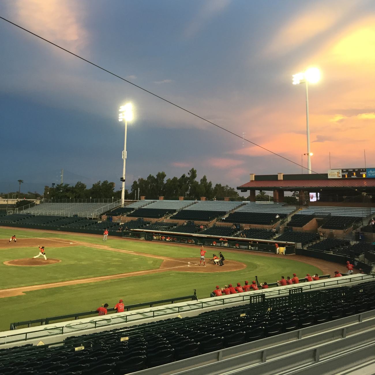 Rookie-level Arizona League game at Scottsdale Stadium, sunset behind the lights, nearly empty stands