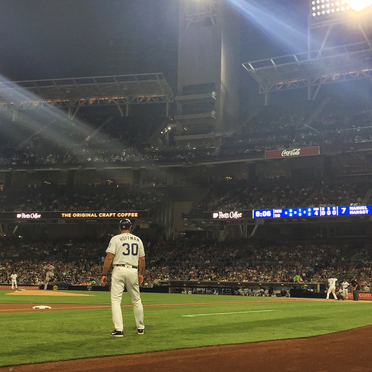 Field level at Petco Park at night, third base coach in the foreground